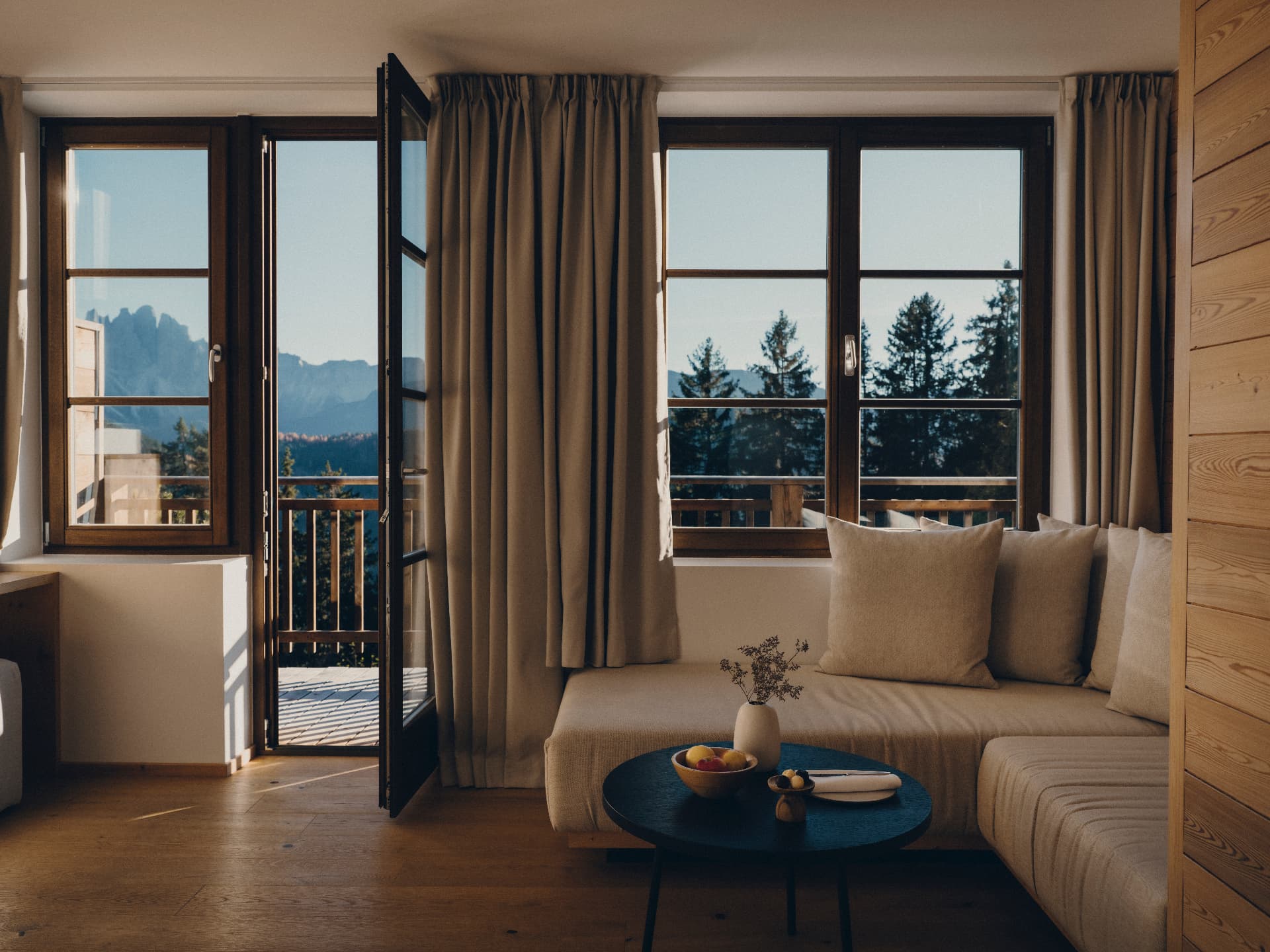 Suite living area with an open balcony door onto the Dolomites