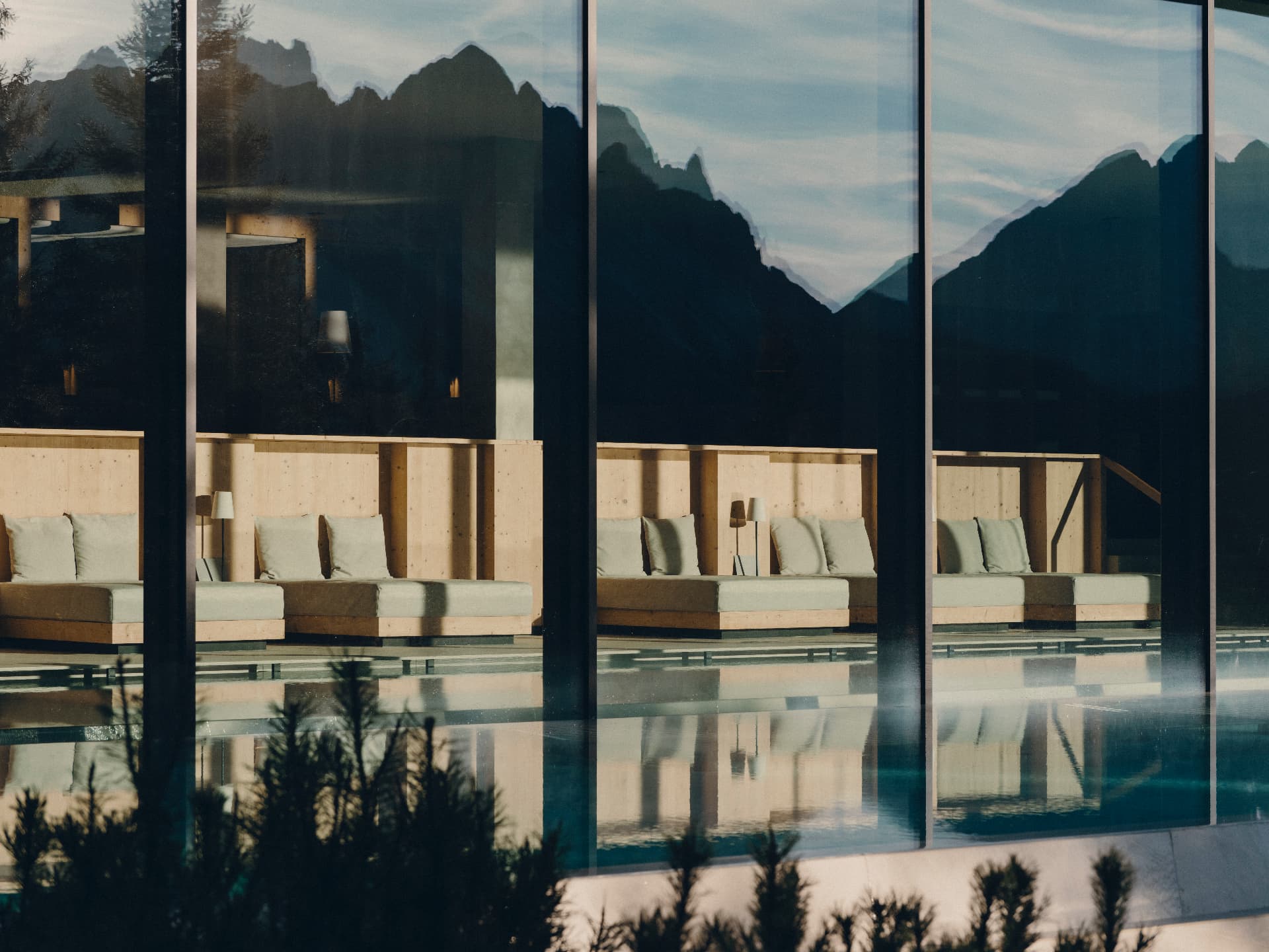 Loungers and the Dolomites reflected in the FORESTIS pool glass